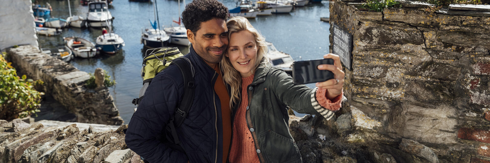 A couple taking a selfie using a smart phone while on holiday in Polperro, Cornwall.