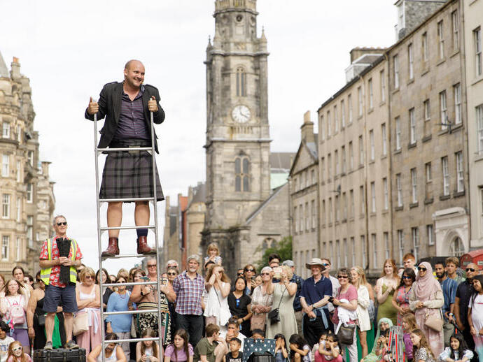 El artista callejero Peter Anderson hace malabares con espadas frente a una multitud en la Royal Mile, Edimburgo, durante el Festival Fringe 2022.