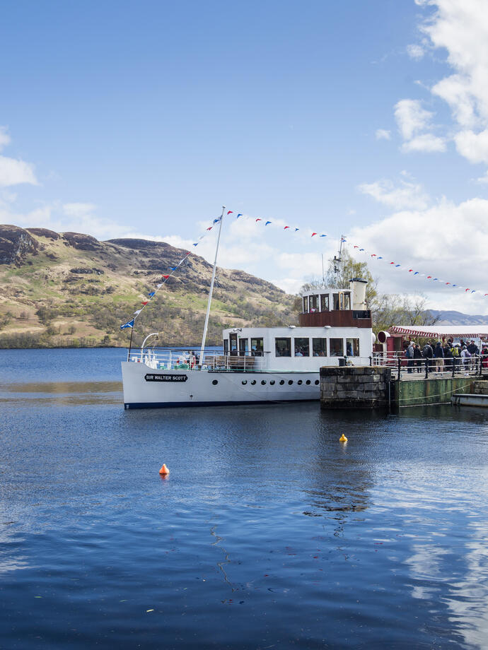 Des personnes embarquant sur un bateau à vapeur sur un lac depuis un embarcadère.