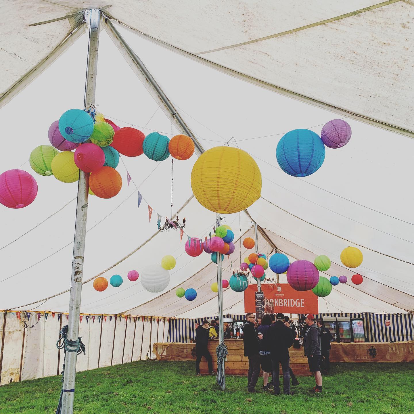 Summer-party time, people in a large tent with colourful lanterns