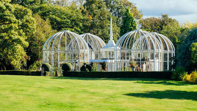 Quatre grandes orangeries en forme de cage disposées sur l'herbe