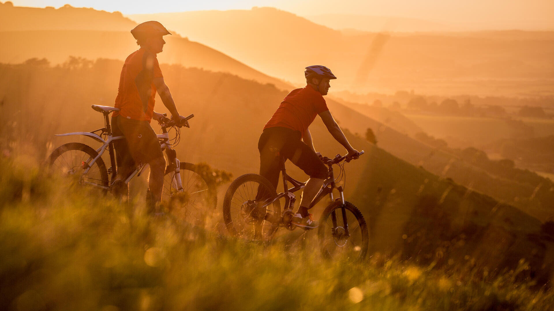 Two men on mountain bikes cycling at Devil's Dyke. Sunrise
