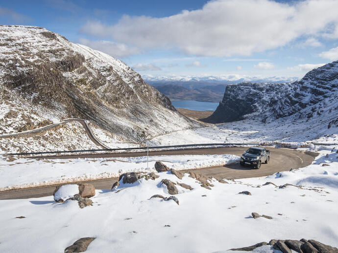 A car on a mountain road surrounded by snow