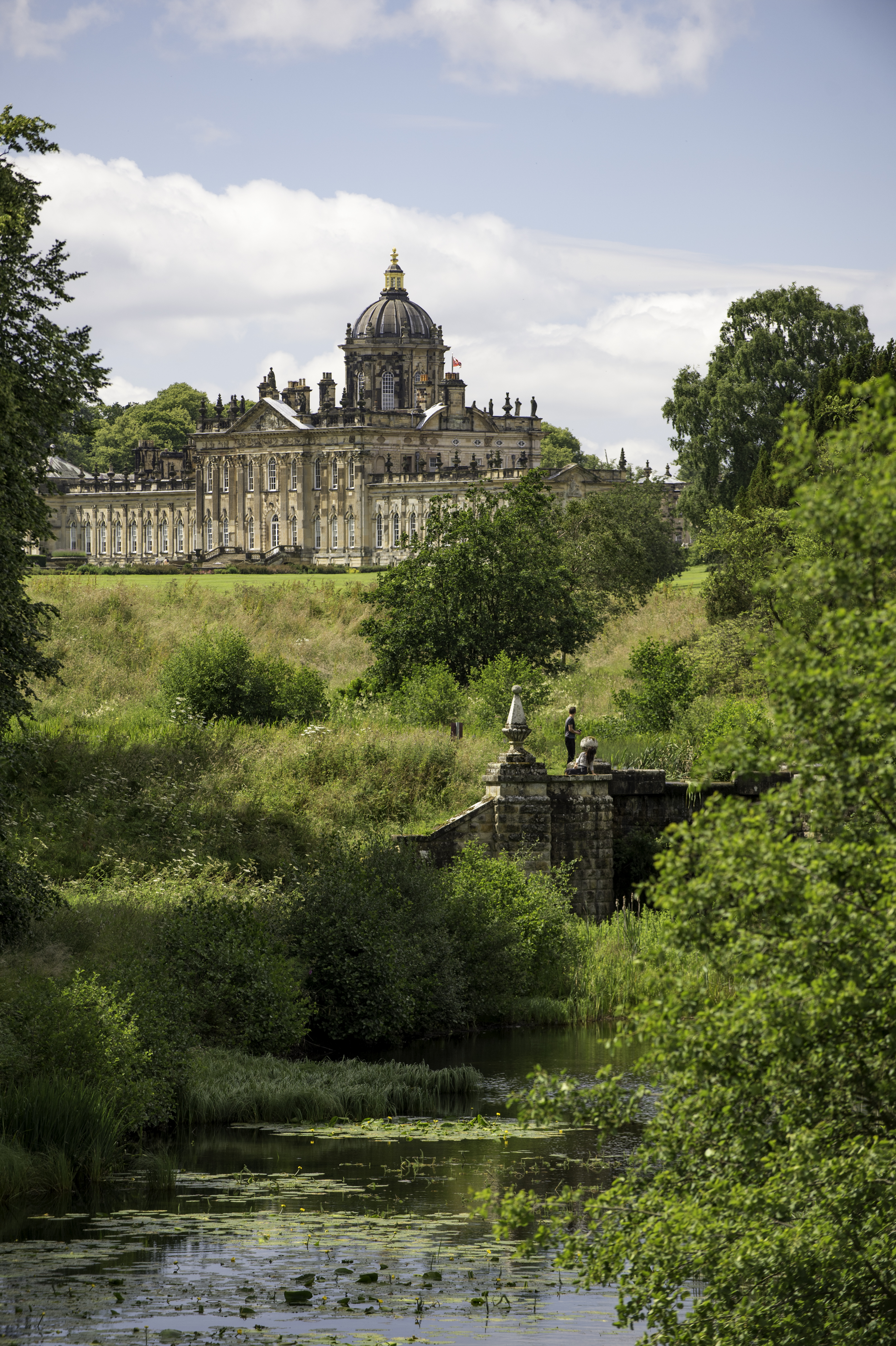 Large country house surrounded by trees with stream in the foreground