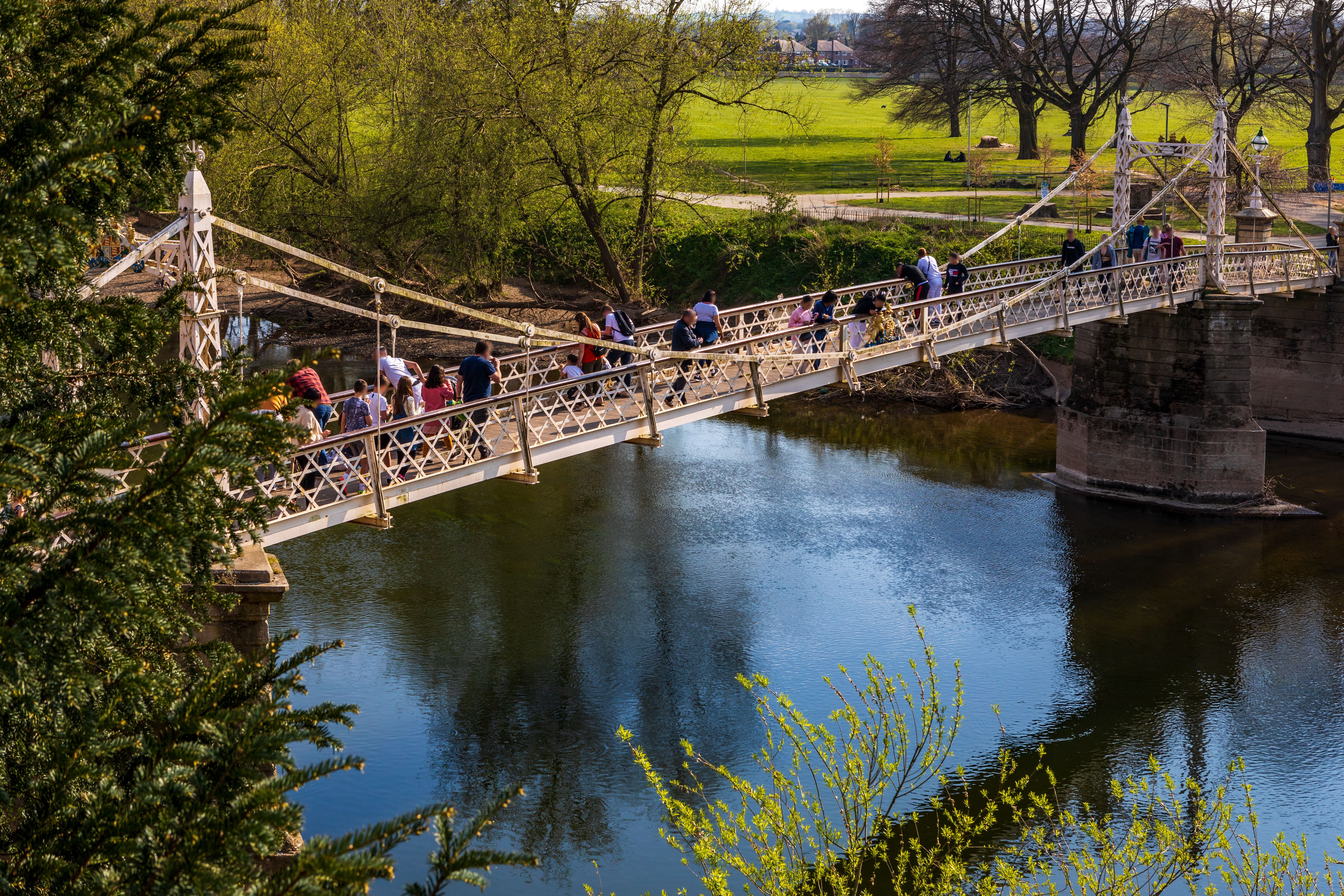 People on a suspension bridge over a river