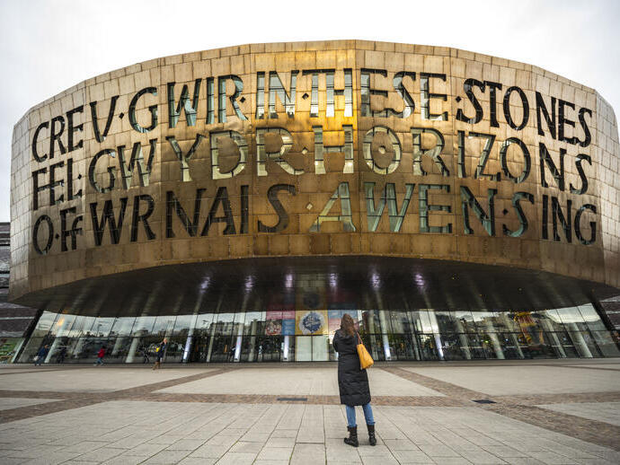 Person, die zur Fassade eines bronzenen Gebäudes aufblickt