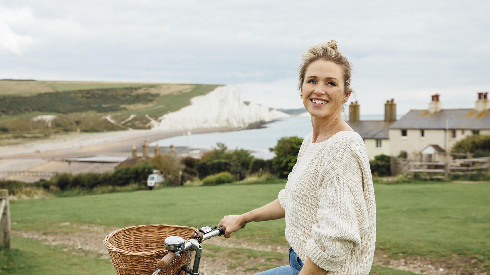 Lächelnde Frau auf einem Fahrrad mit weißen Klippen im Hintergrund
