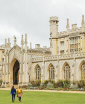 Two women walking across the grass in front of an historic building