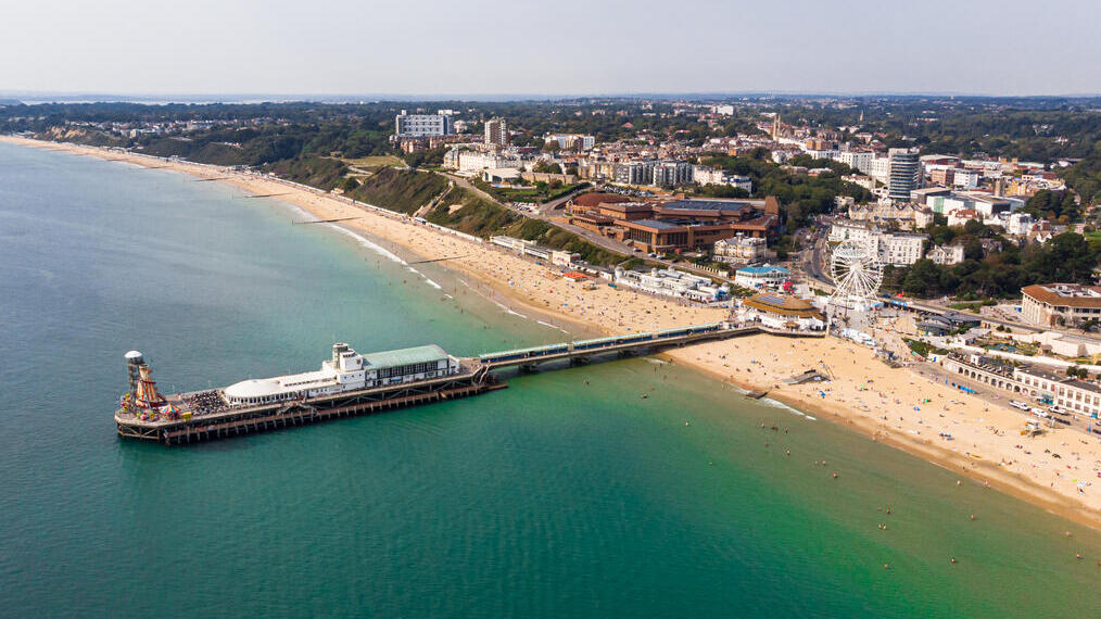 Vista aérea de una ciudad costera con una playa de arena y un parque de atracciones.