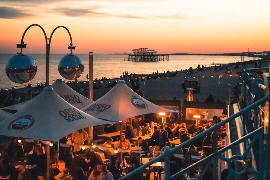 People enjoy drinks at Ohso Social bar on Brighton seafront at sundown