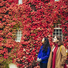 Two women in front of a building covered in red Virginia creeper