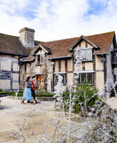 Man and woman walking outside a Tudor house