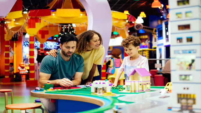 Mother, father and son laughing whilst playing with Lego