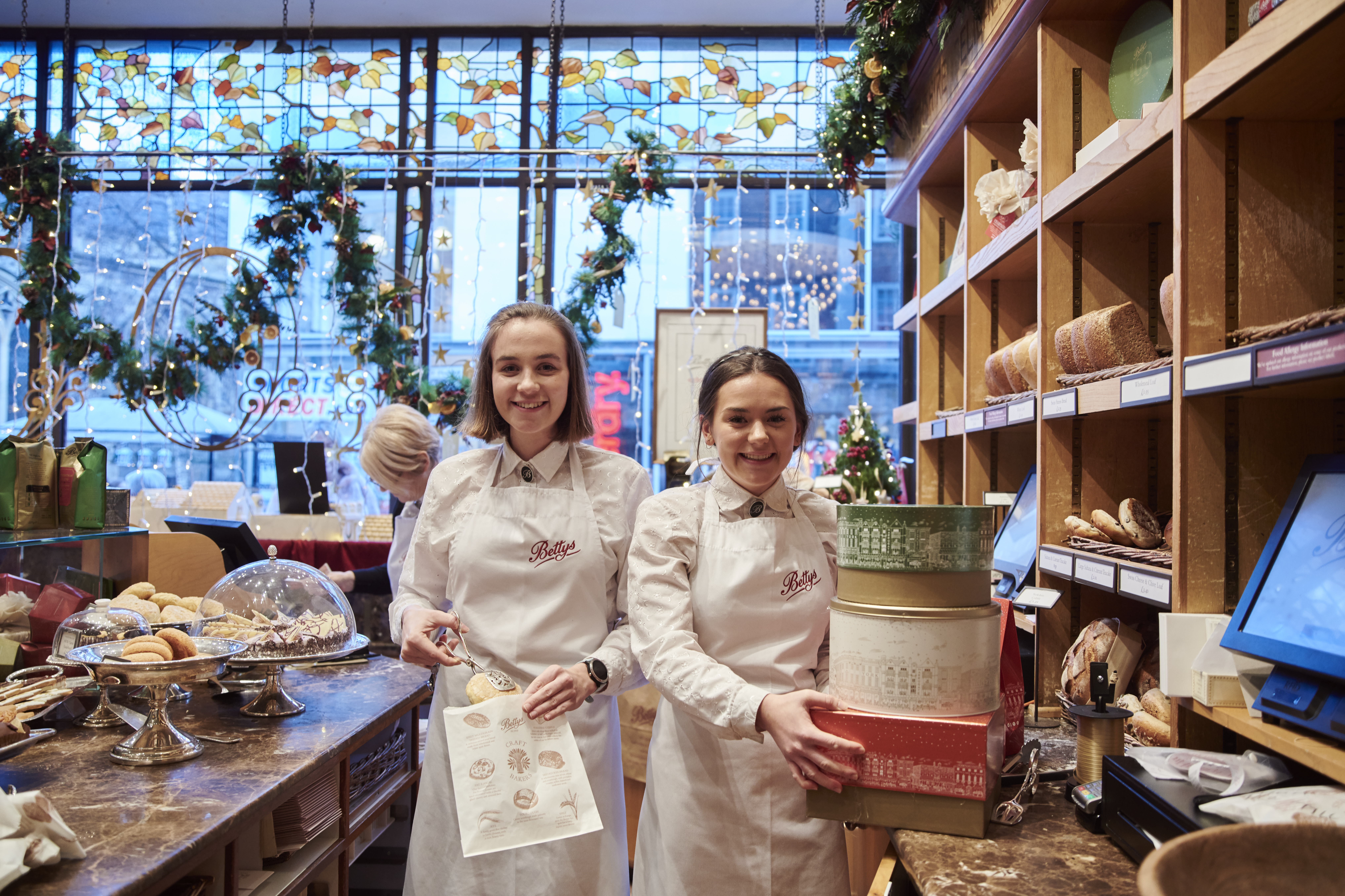 Two waitresses stood behind counter of tea shop