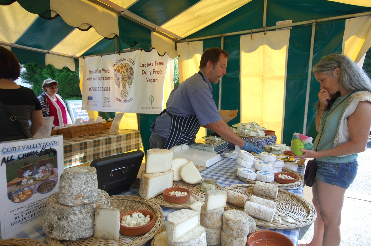 Un hombre vendiendo queso en el mercado de productores locales de St Dogmaels