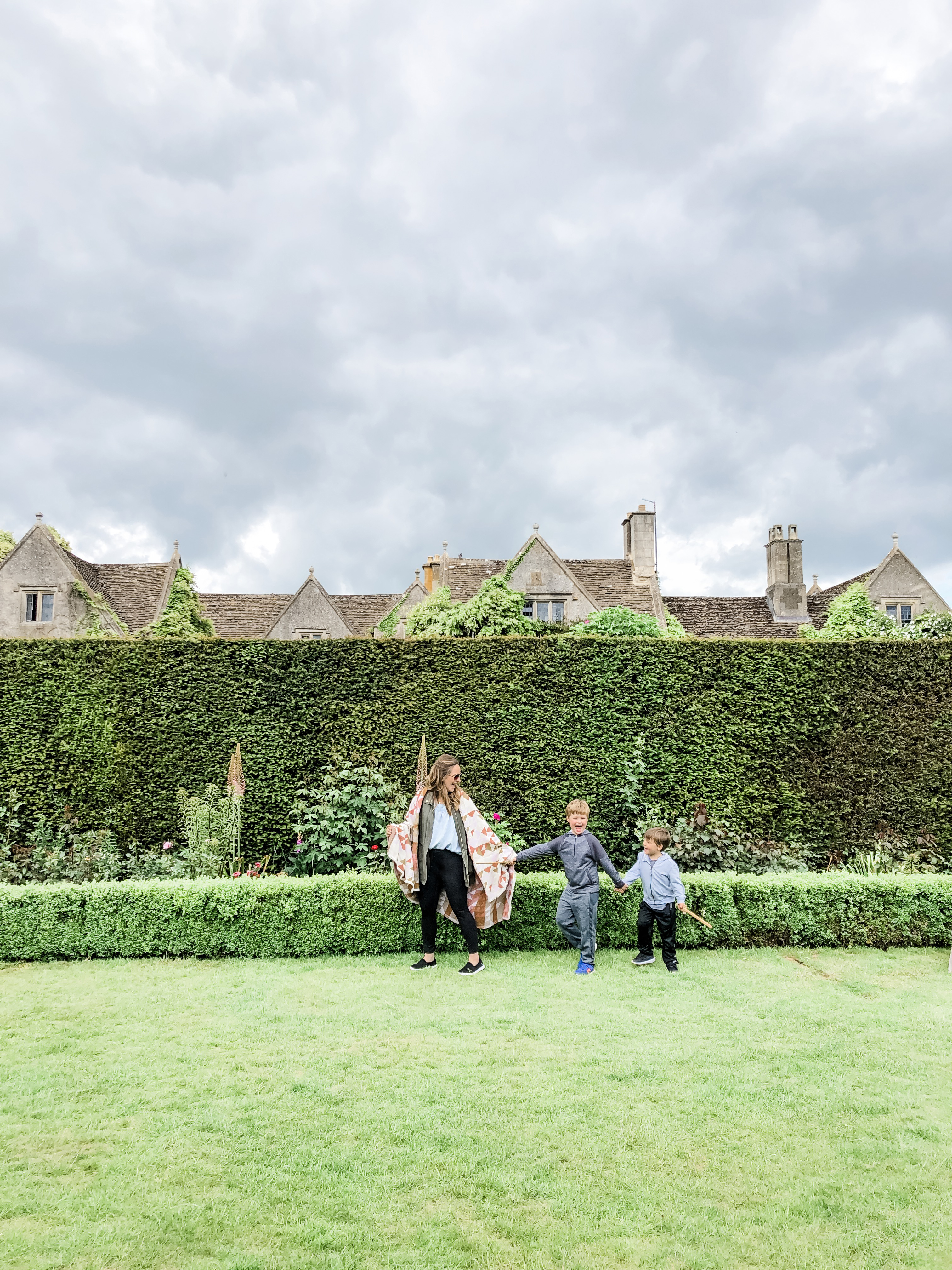 Mother and sons standing in garden in front of a tall hedge