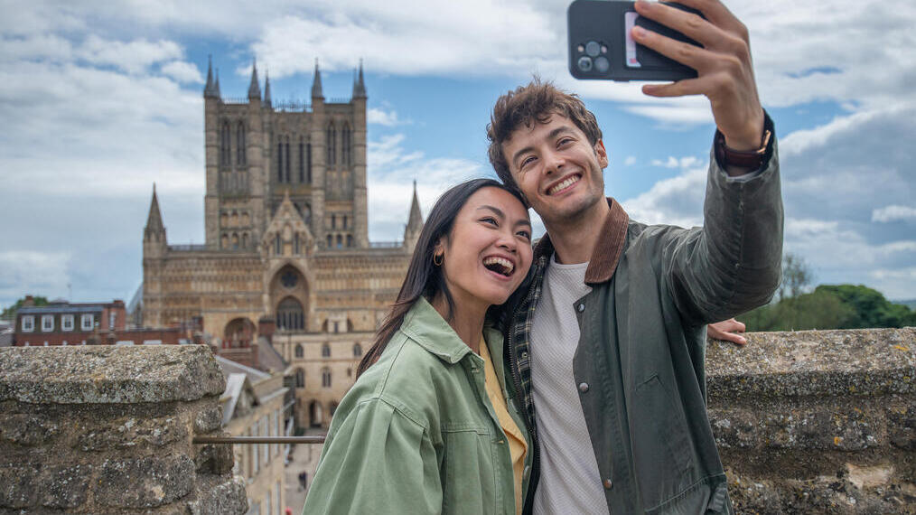 Un uomo e una donna sorridono e si scattano un selfie davanti a una cattedrale