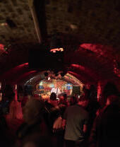 Brick tunnel-shaped room with music act on stage.