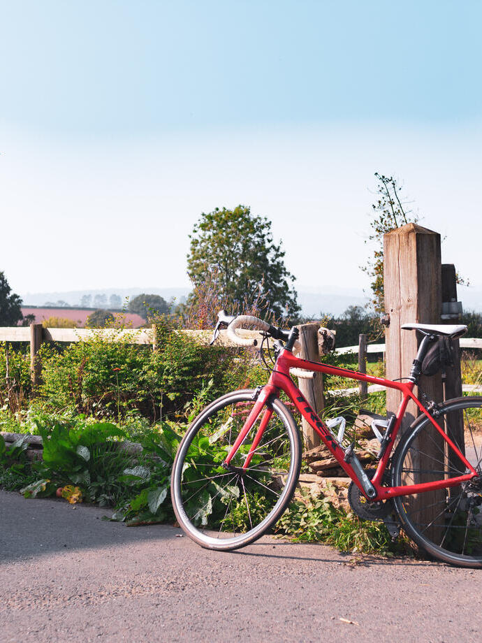 A red bicycle resting against a wooden post