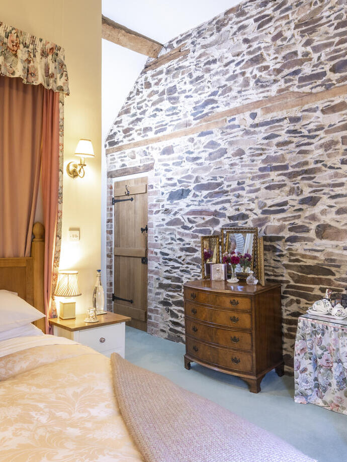 View of a bedroom at a guest house with bed and stone feature wall