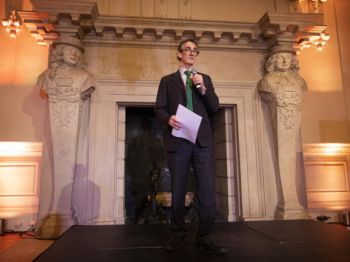 A man on a stage welcoming delegates at a trade event