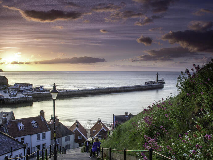 شخصان على درجات منحدر صخري بجانب البحر