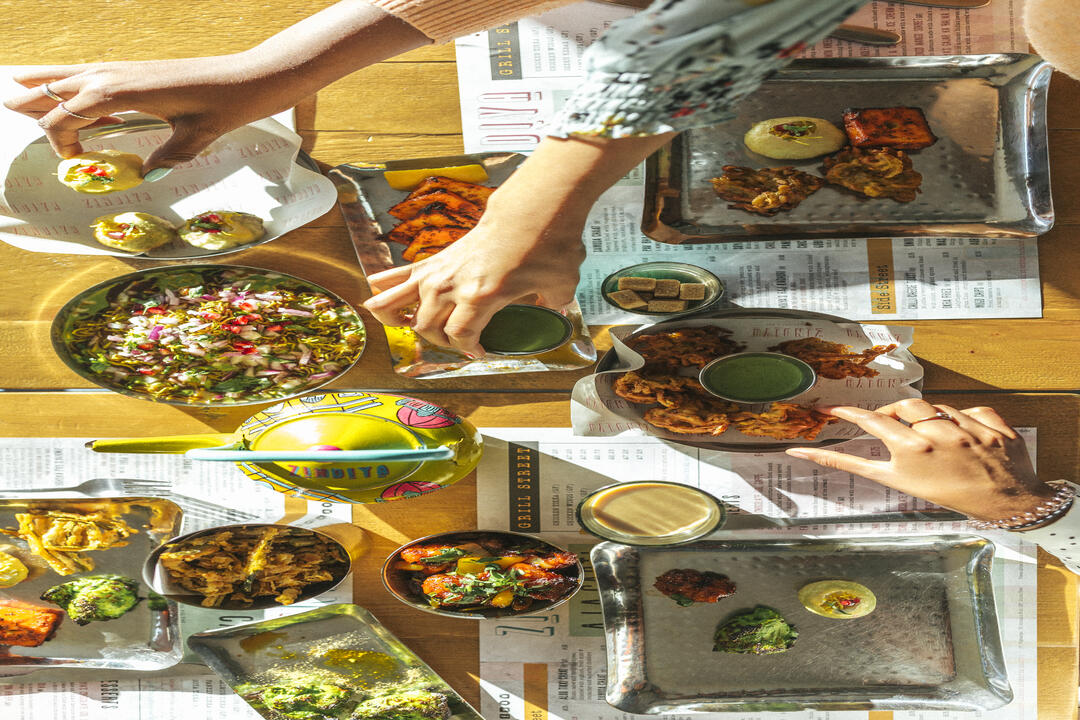 Gente comiendo comida india de una selección de platos sobre una mesa
