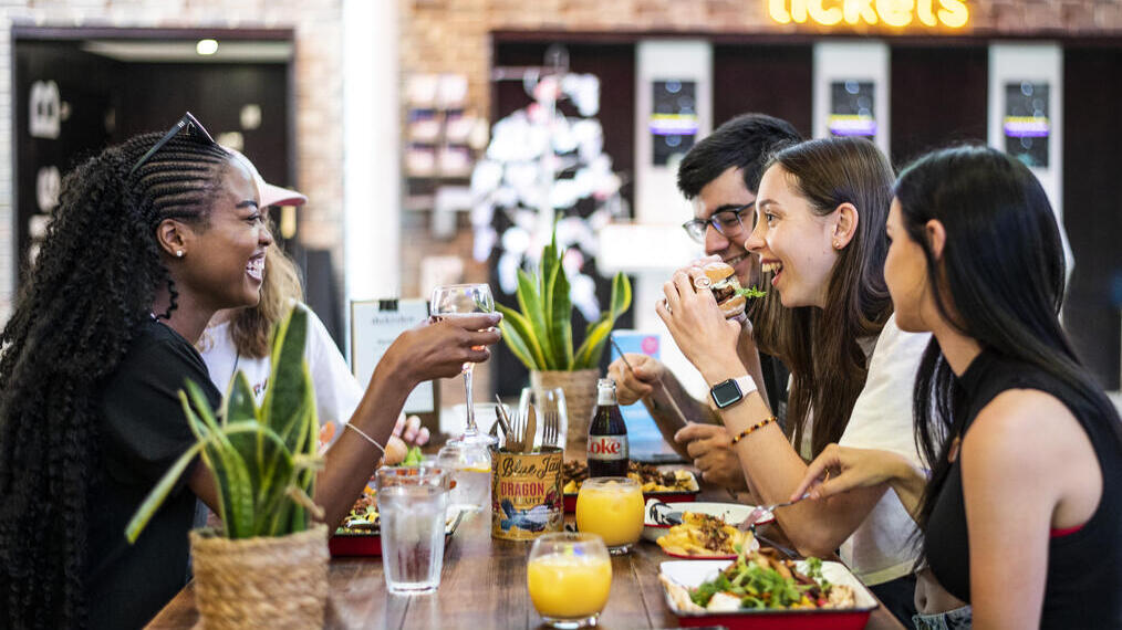 Un groupe de personnes assises sur un banc en train de manger au Storyhouse à Chester