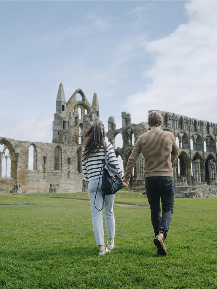 A man and woman walking towards a heritage Abbey building