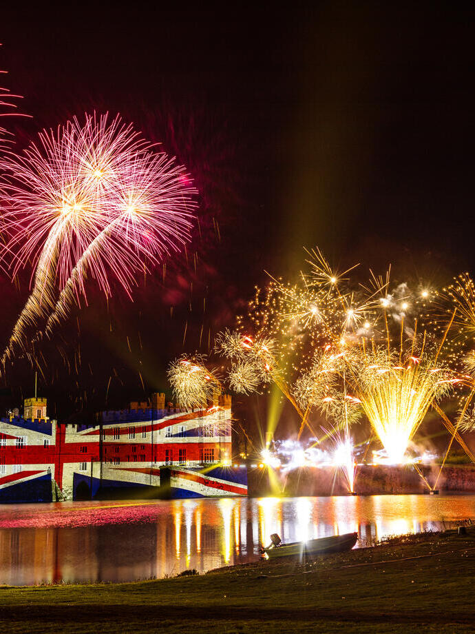 Fireworks and a large union jack illumination on a castle wall at night