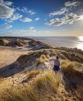 Woman walking along sand dunes at Formby beach