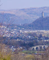 Aerial view of a town with a hilltop statue in the background.