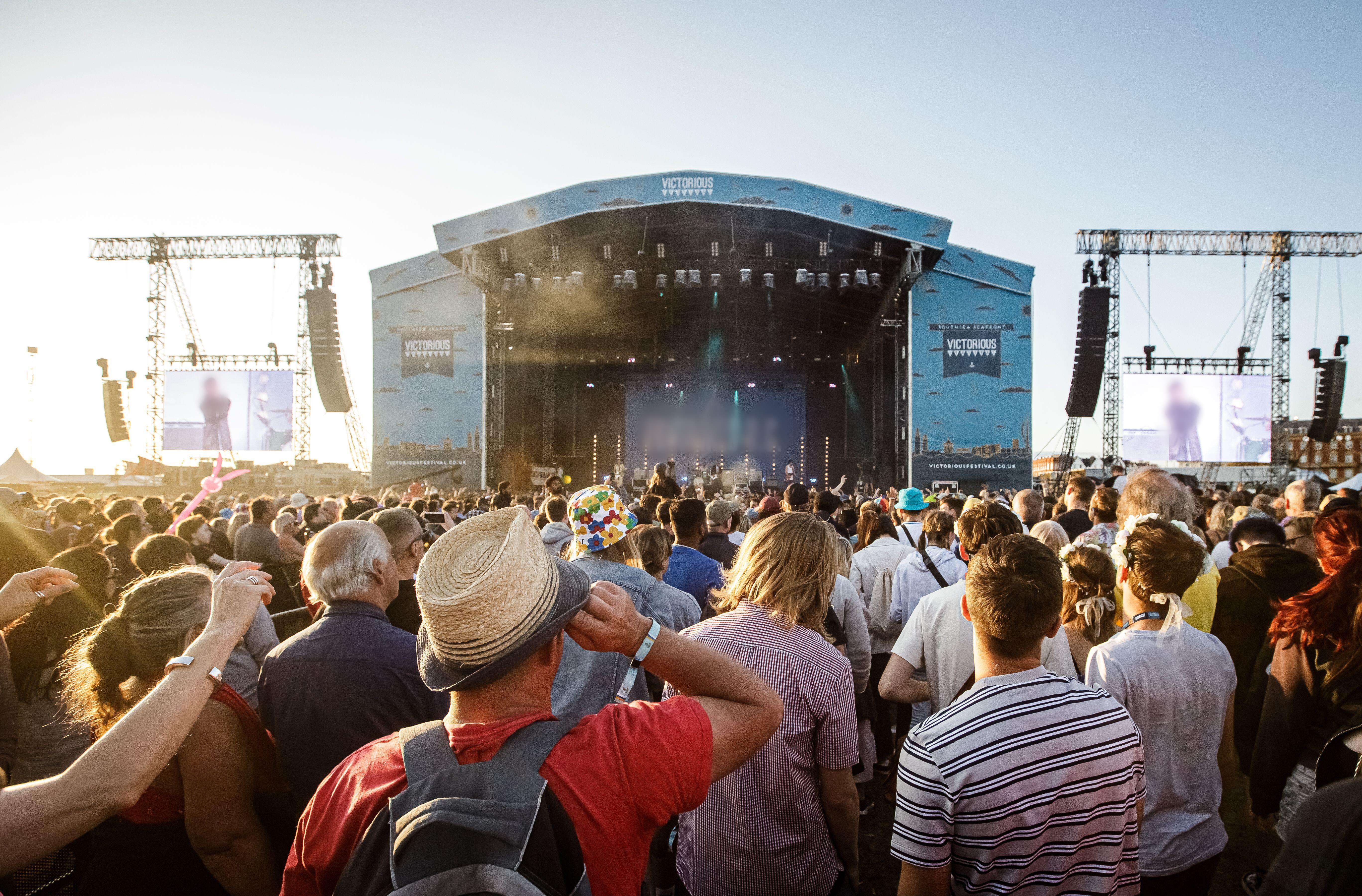 A large crowd enjoying a band on stage at an outdoor concert.