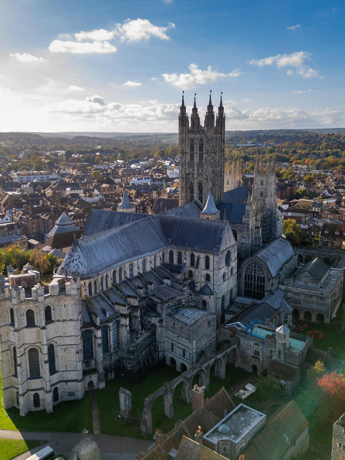 Aerial view of cathedral with tall towers surrounded by autumnal trees