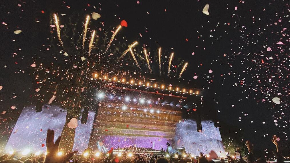Audience watching stage at night with fireworks in the background