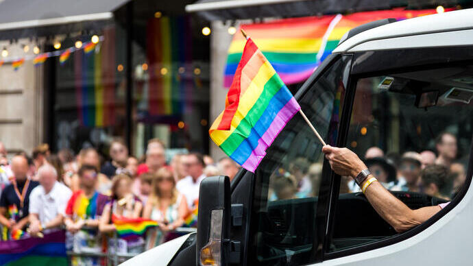 Crowds of people celebrating at a Pride parade in a city centre.