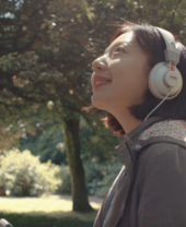A woman in headphones looking out in a garden at St Fagans National Museum of History, Cardiff