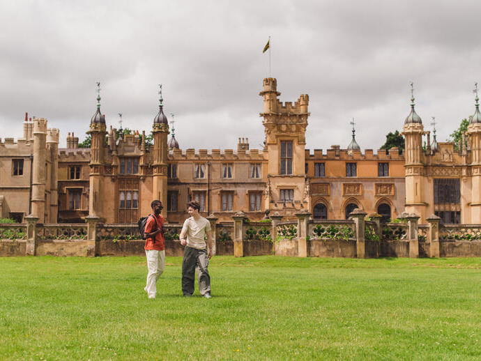 Two young men walk in the grounds of a heritage house
