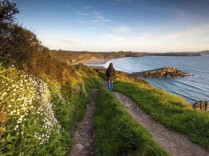 Walker traversing a coastal beach path overlooking a large empty beach.