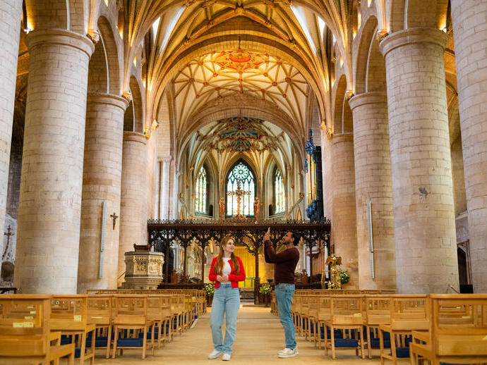 A woman and man explore the interior of an Abbey