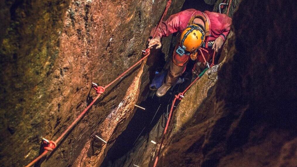 A man exploring through a cave system at Cornwall Underground Adventures