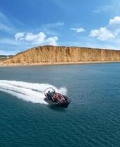 Ein Schnellboot mit einer Gruppe, das durch den Ozean der Lyme Bay rast