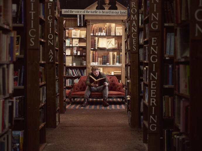 Mann in einer Buchhandlung, der ein Buch liest