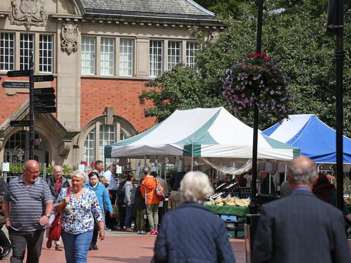 People visiting an outoor produce market near a historic building.