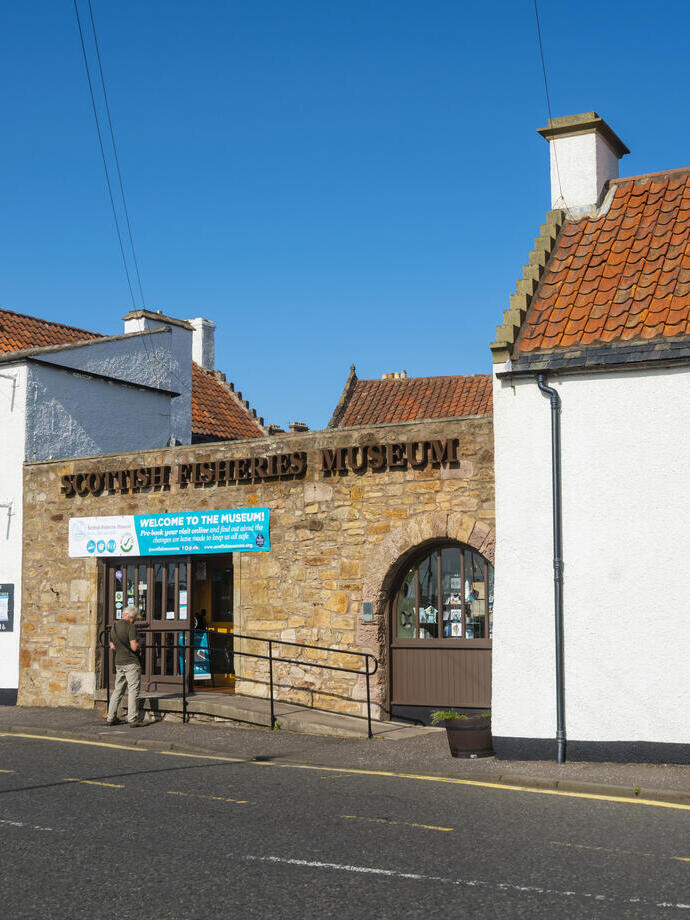 Three white houses and a brick entranceway with colourful signage on the front.