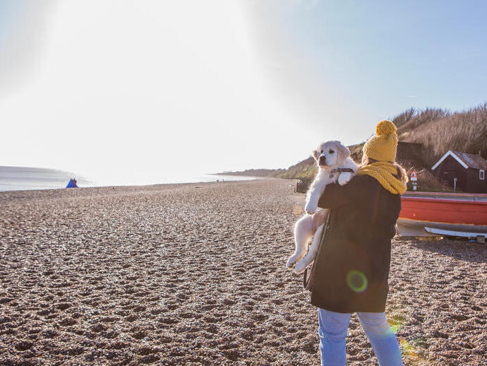 Une femme portant un chien sur la plage de Dunwich