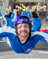 A person riding the iFLY Indoor Skydiving experience with a crowd of people watching behind