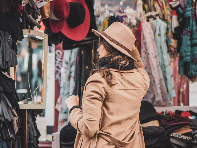 Eine Frau probiert Hüte an einem Stand auf dem Portobello Road Market in London
