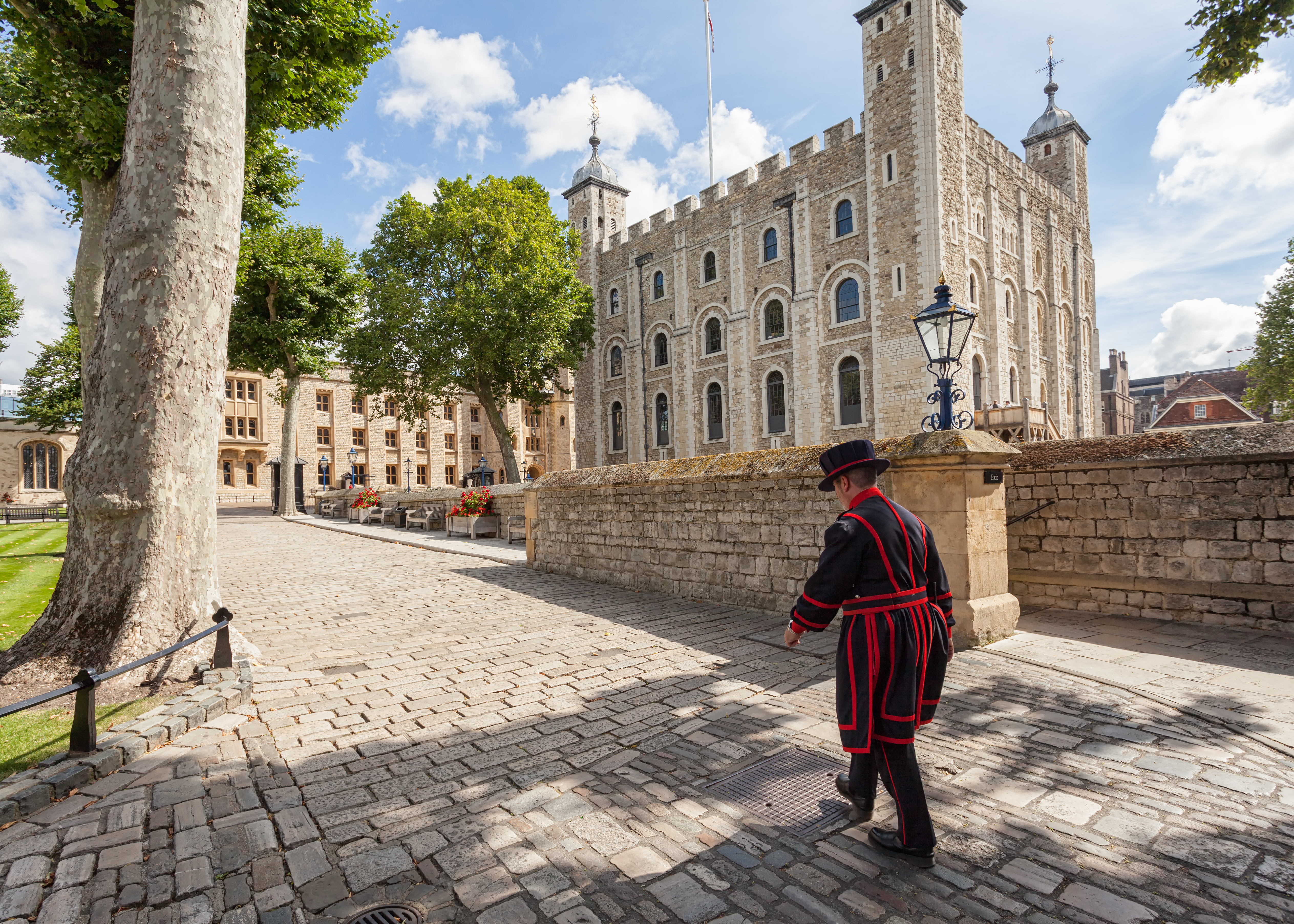 Beefeater walking by the Tower of London on a sunny day