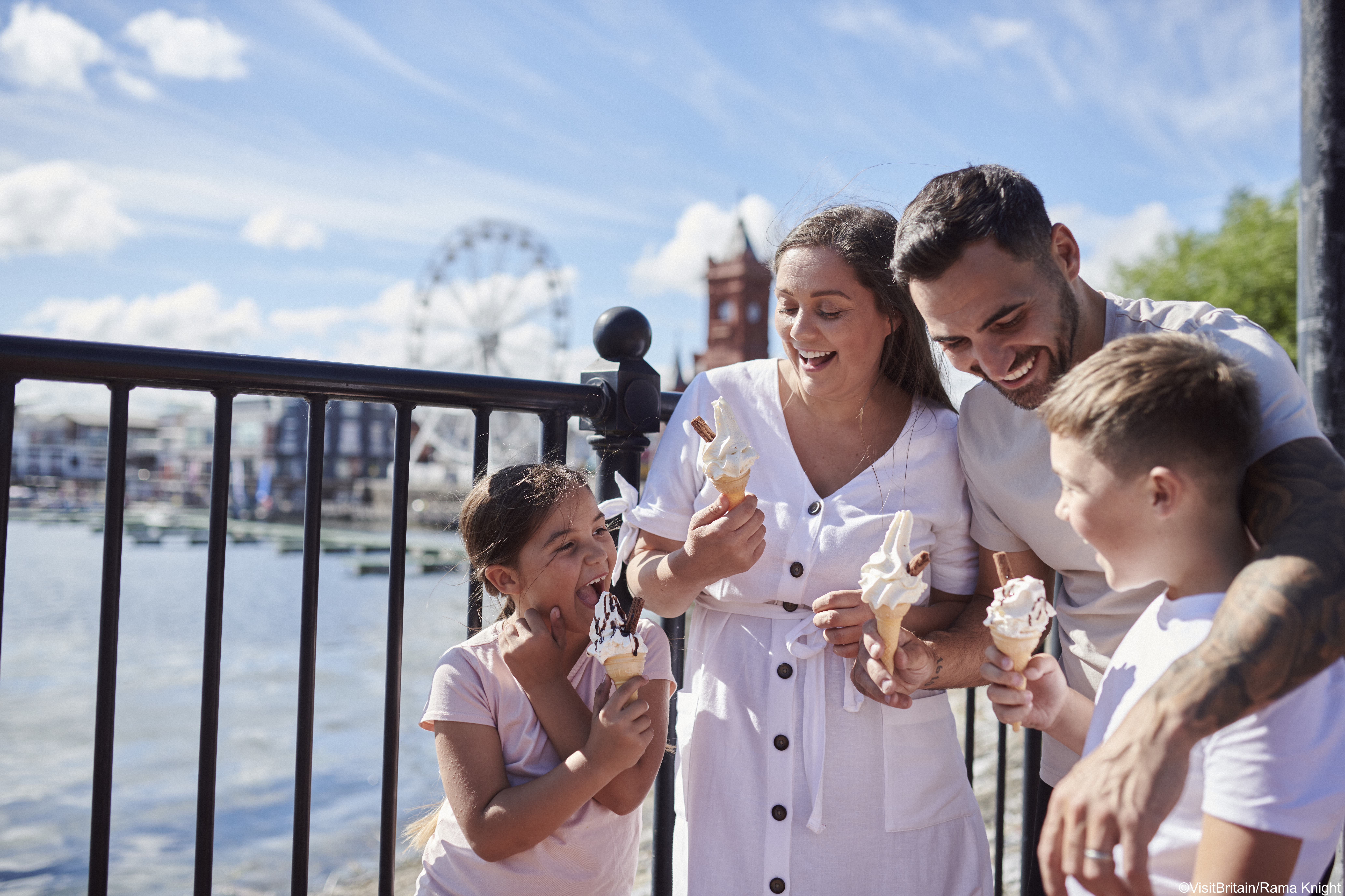 Family eating ice cream in a bay with a Ferris wheel behind